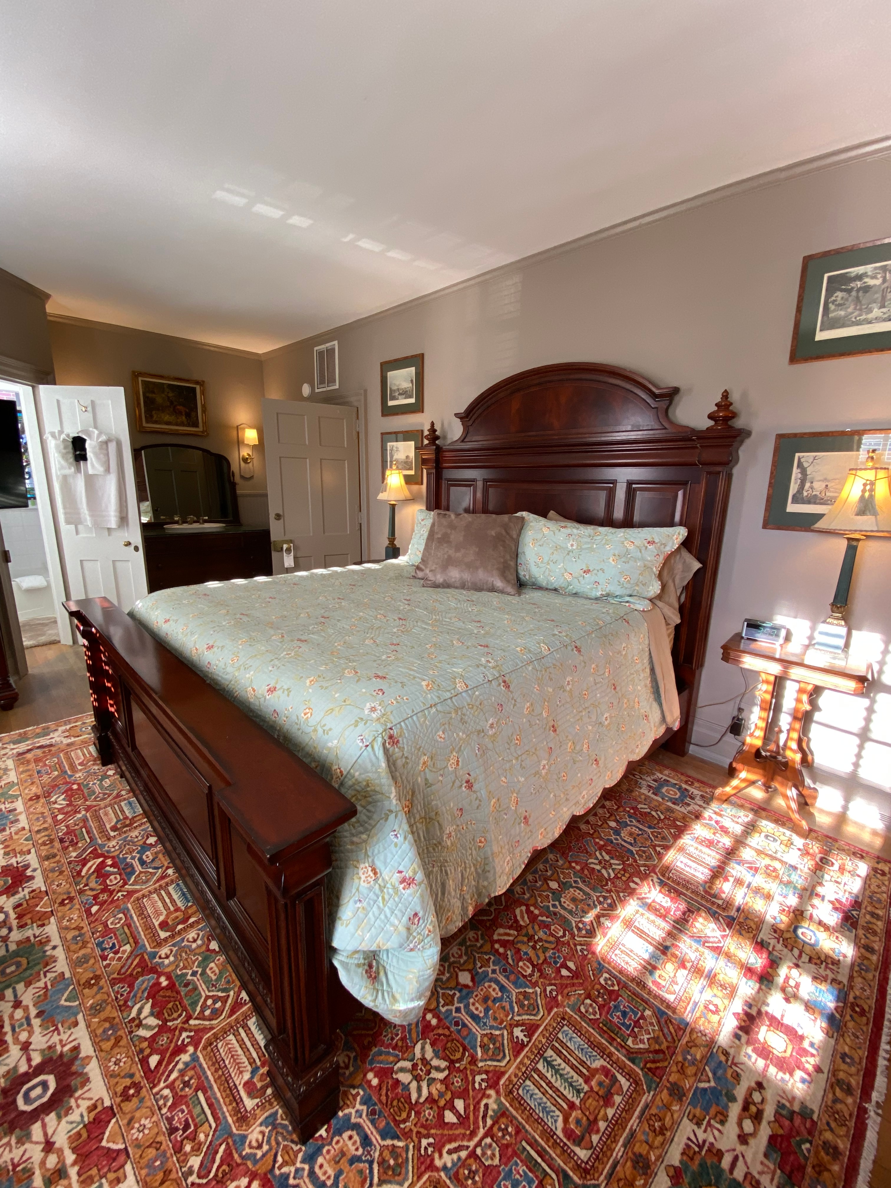 A cozy bedroom featuring a wooden bed with a floral quilt, bedside tables, and a decorative rug.