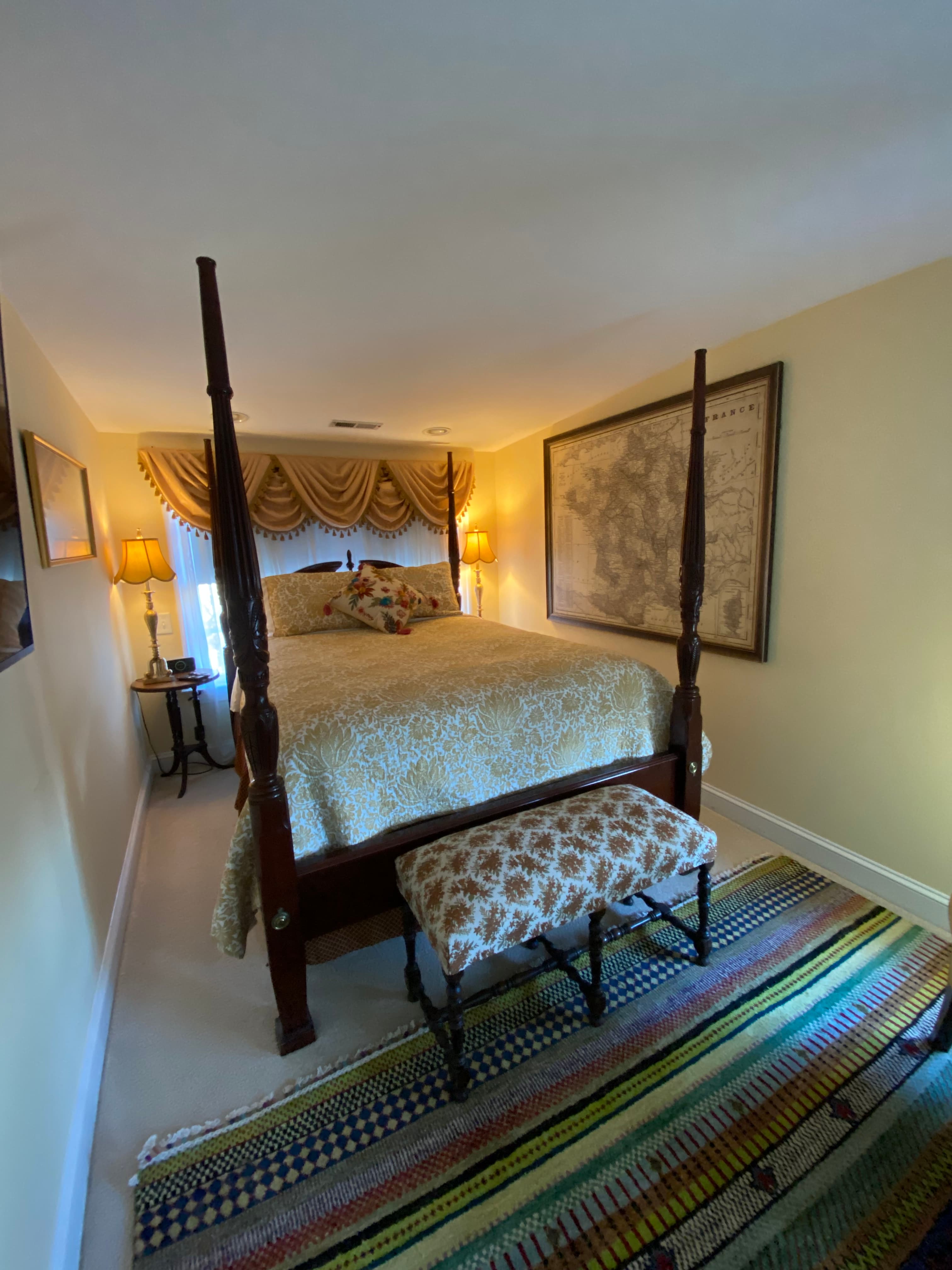 Cozy bedroom featuring a four-poster bed, decorative bench, and warm lighting.