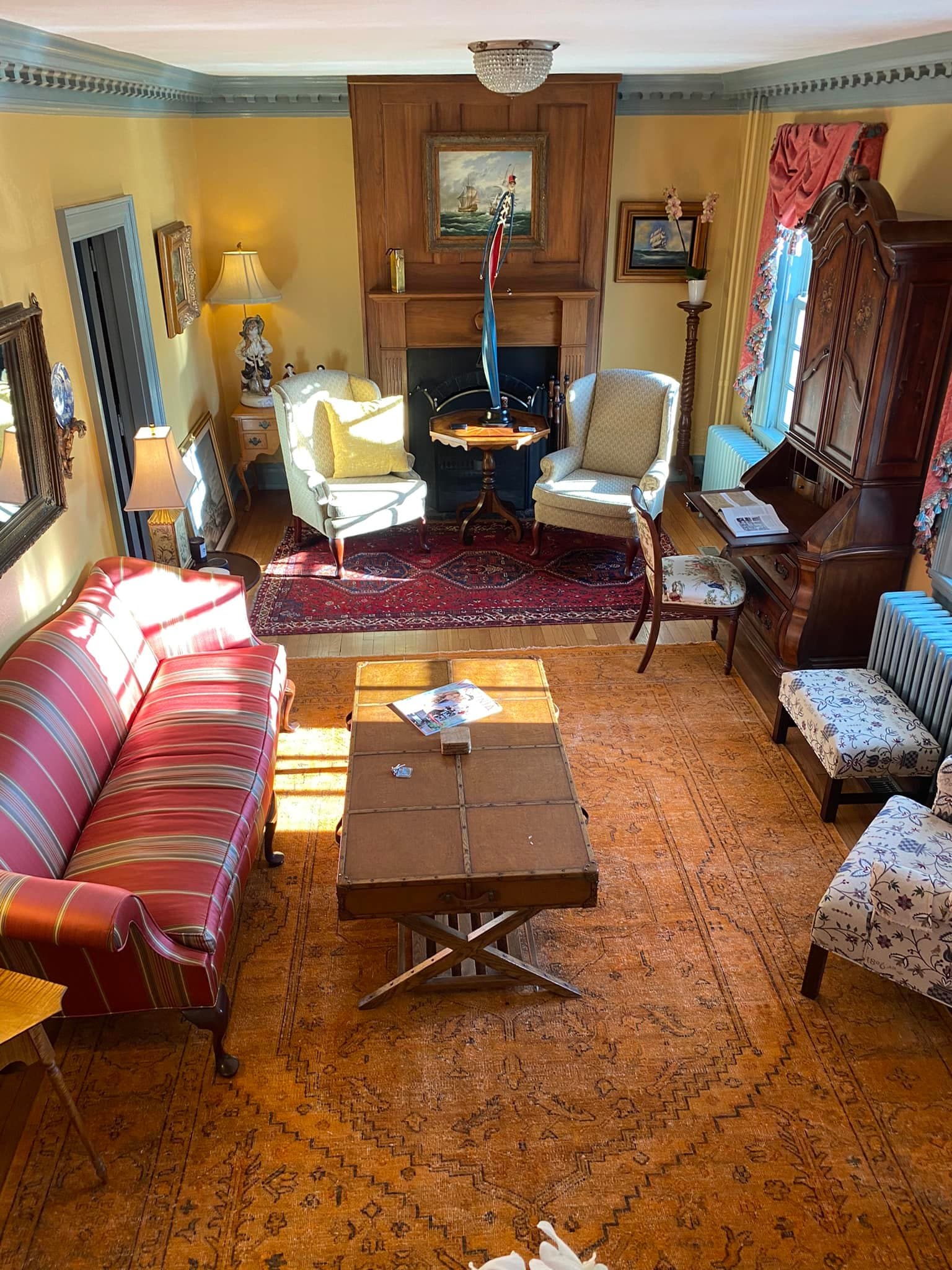 A cozy living room featuring a striped sofa, a wooden coffee table, and two armchairs beside a fireplace.