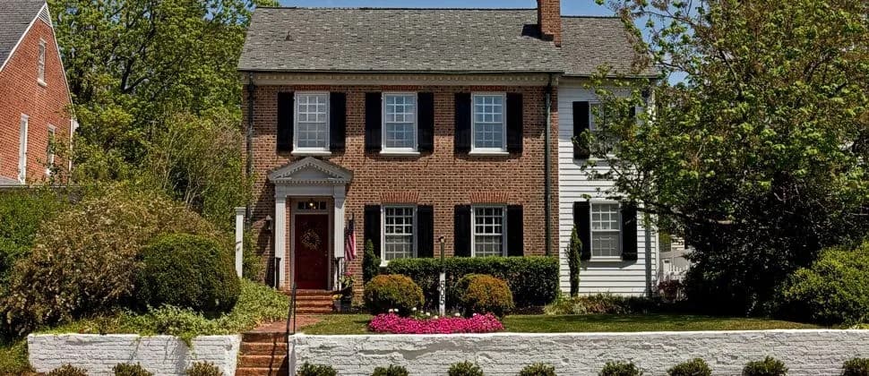A charming two-story brick house with white trim and a well-maintained garden.