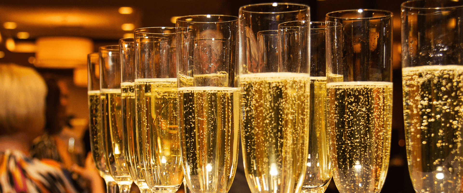 A row of champagne flutes filled with bubbly liquid.