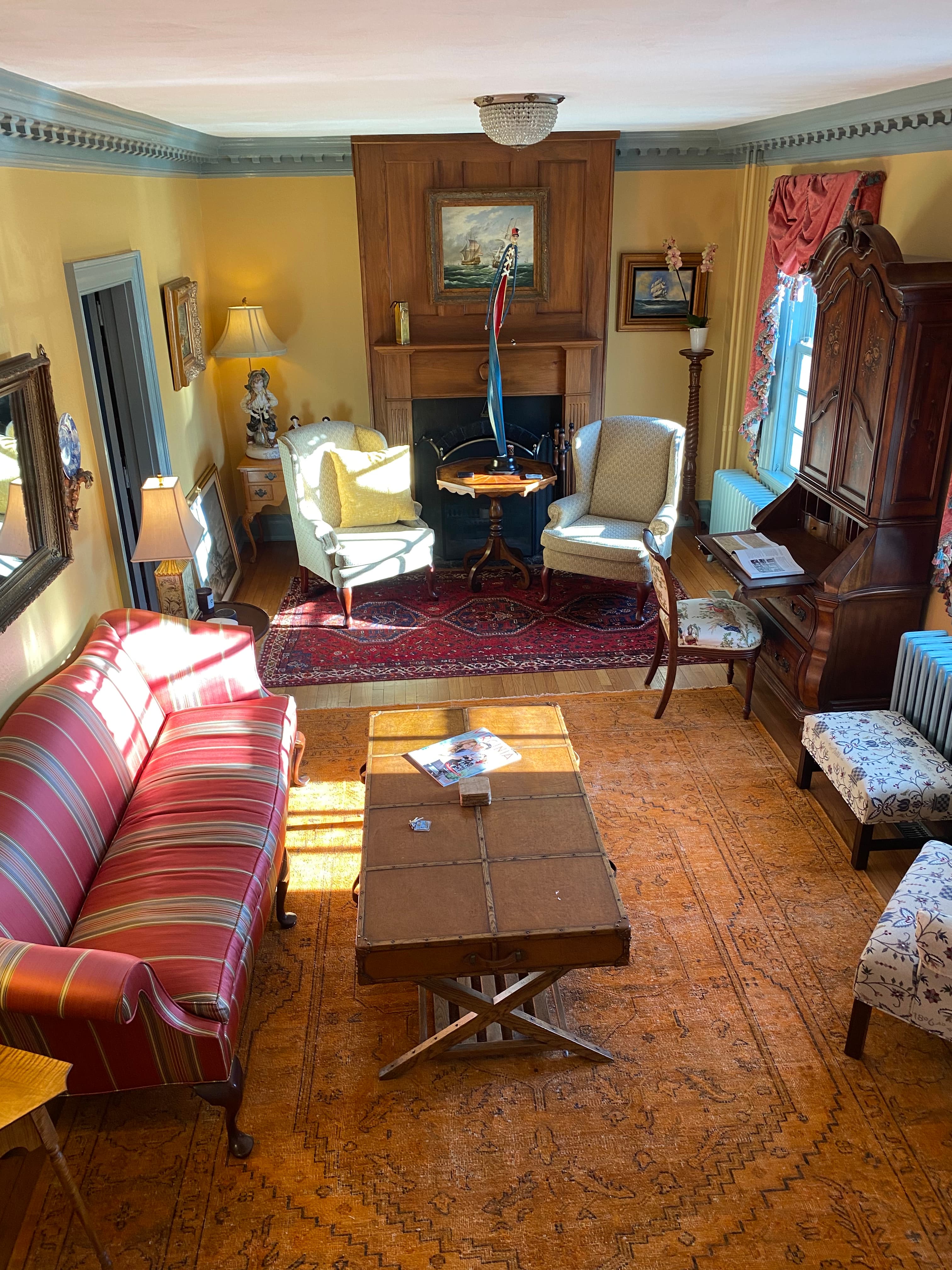 A cozy living room featuring a striped sofa, two armchairs, a wooden coffee table, and warm lighting.
