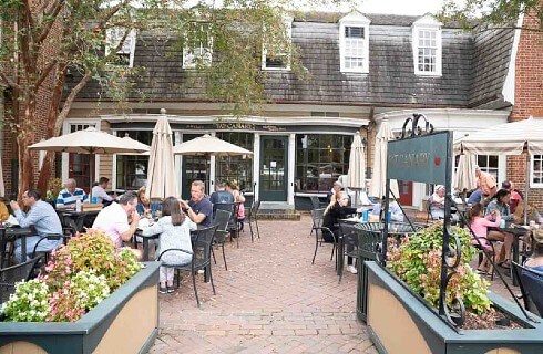 Outdoor patio seating area full of people in front of a quaint shop