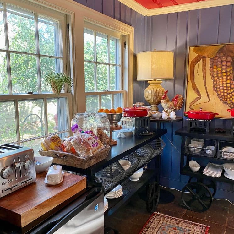 Breakfast buffet area with two carts holding dishes, jars of cookies and a basket of breads