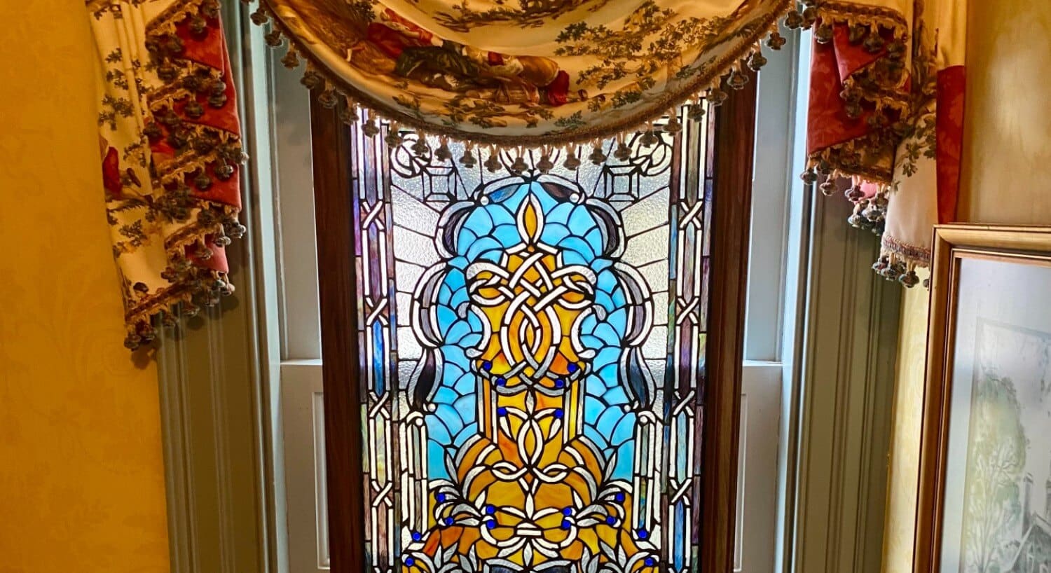 Beautiful stained glass window with a floral curtain valence draped at the top