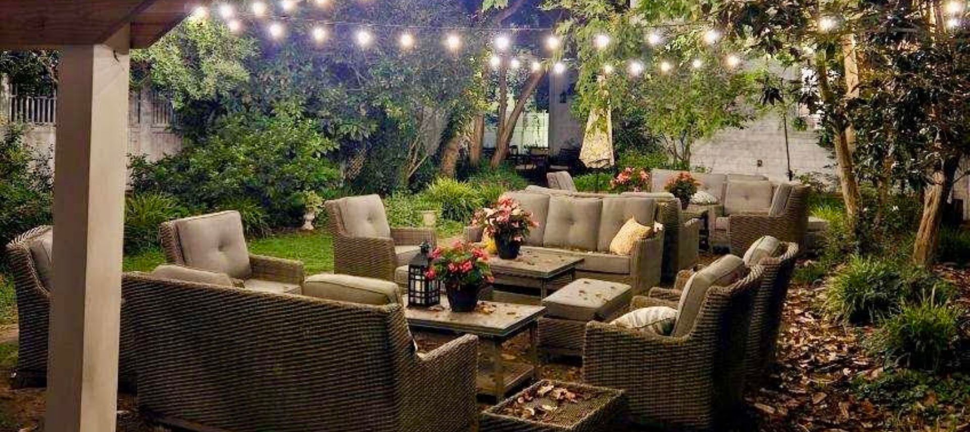 Backyard oasis with patio couches and chairs under strings of little white lights